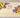 Ivory sheet cake decorated with yellow buttercream sunflowers, purple blossoms and green leaves.