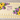 Ivory sheet cake decorated with yellow buttercream sunflowers, purple blossoms and green leaves.